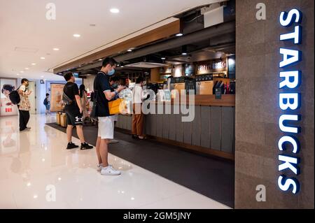 Les clients font la queue dans la chaîne multinationale américaine Starbucks Coffee Store à Hong Kong. Banque D'Images