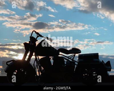 La forme de la moto miniature avec la fenêtre et le ciel nuageux à l'arrière Banque D'Images