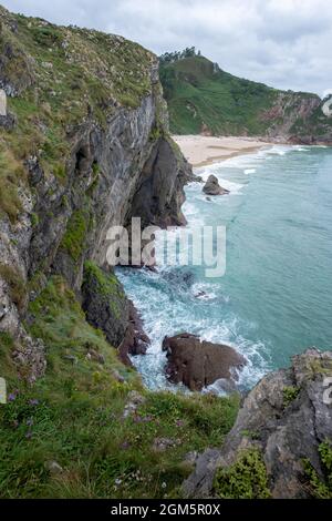 Falaises de la plage d'Andrin à Llanes Asturias Espagne, paysage de bord de mer avec eaux turquoise, falaises vertes et une plage de sable blanchâtre, verticale Banque D'Images