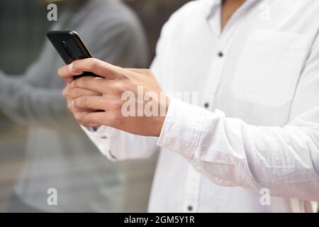 Gros plan Homme à envoyer des SMS sur un téléphone portable. Photo de haute qualité. Banque D'Images