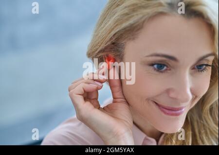 Femme souriante avec prothèse auditive près de l'oreille Banque D'Images