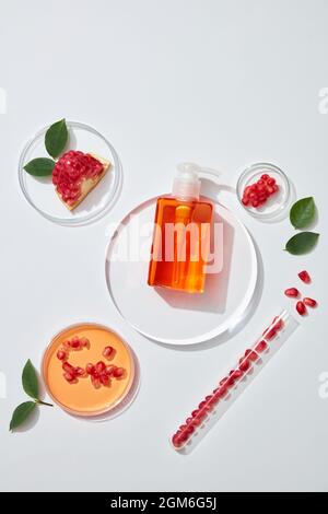 Flacons cosmétiques avec extrait de grenade, vue de dessus. Gros plan et décor blanc. L'étiquette vierge pour la maquette. Boîte de Petri en verre Banque D'Images