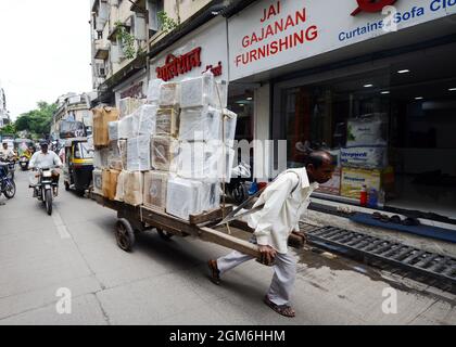 Un homme de Marathi tirant un chariot chargé de caisses lourdes à Pune, en Inde. Banque D'Images