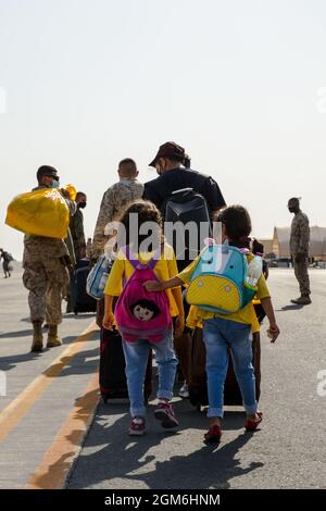 Les marines américaines du combat Logistics Battalion 13 avec le centre de contrôle d'évacuation, aident les évacués afghans à porter leurs bagages à l'avion de la base aérienne d'Al Udeid, Qatar, le 3 septembre 2021. Le ministère de la Défense s'est engagé à appuyer l'évacuation des citoyens américains, des demandeurs de visa d'immigrant spécial et d'autres personnes à risque en provenance d'Afghanistan. (É.-U. Photo du corps marin par lance Cpl. Kyle Jia) Banque D'Images