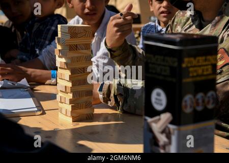 Les enfants évacués jouent à un jeu de construction de tours avec un Airman de la US Air Force lors de l'opération alliés refuge à la base aérienne de Ramstein, en Allemagne, le 28 août 2021. Les militaires sont venus de bases partout en Europe et aux États-Unis pour aider les personnes évacuées à se sentir en sécurité pendant qu'elles attendent leur transport vers les lieux de transport. (É.-U. Photo de la Force aérienne par Stephanie Gelardo, avitrice principale) Banque D'Images