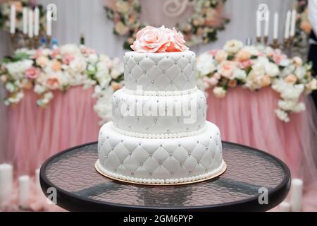 un gâteau de mariage blanc à plusieurs niveaux et des fleurs roses sur le dessus. Grand gâteau. Gâteau d'anniversaire Banque D'Images