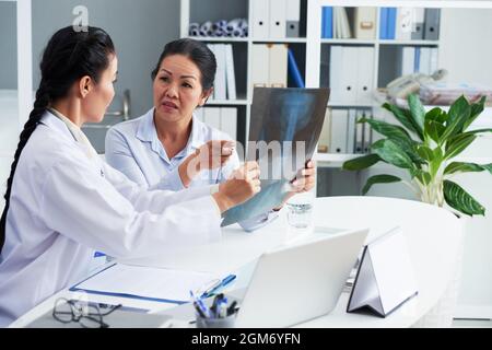 Femme âgée effrayée discutant de sa radiographie thoracique avec un médecin généraliste lors d'un examen annuel Banque D'Images