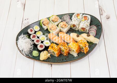 Plateau de sushis assorti avec nigiri de saumon, rouleau de californie uramaki, thon et avocat maki, algues nori, nouilles de riz, wasabi et ginseng Banque D'Images