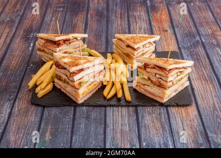 Super club sandwiches avec beaucoup de plats remplis de bacon, oeufs frits, laitue, fromage, ketchup, Jambon, filets de poulet et frites. Banque D'Images