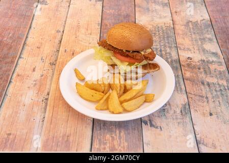 Tranches panées de filets de poulet avec tomates et laitue et une portion de pommes de terre frites de luxe Banque D'Images