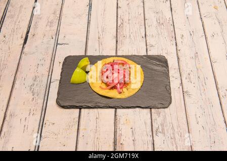 Cochinita pibil taco sur tortilla de maïs et quartiers de lime sur plaque d'ardoise noire Banque D'Images