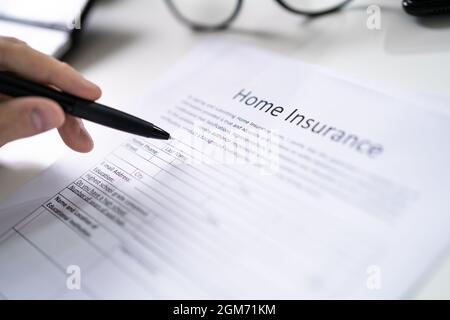 Man.remplir le formulaire d'assurance habitation. Écriture à la main Banque D'Images