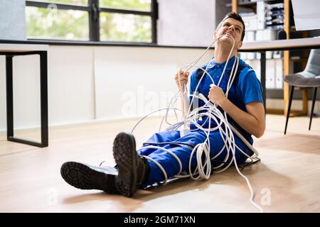 Un technicien ou un technicien de maintenance de service emmêlé et toronné par des câbles Banque D'Images