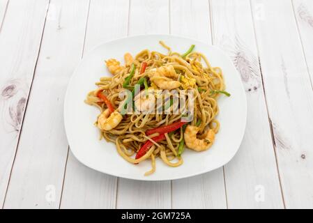 Les nouilles du restaurant chinois sautées de crevettes, de légumes, d'œufs braisés et de poivrons rouges et verts Banque D'Images