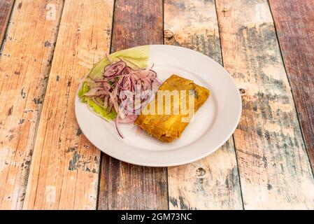 Tamale de maïs farci de ragoût de viande cubaine avec beaucoup d'oignon violet cru sur la plaque blanche Banque D'Images