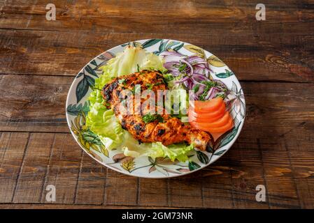 Cuisse de poulet cuite avec une recette de tandoori hindou avec du persil et des tranches de tomate sur une table vintage Banque D'Images