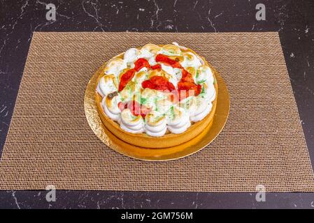 Gâteau au citron décoré de crème farcie et de confiture de fraises sur une table en marbre noir Banque D'Images