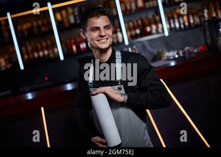 Beau barman en tablier debout au comptoir du bar Banque D'Images