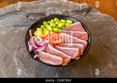 Marqué sur le bol Tataki au thon rouge en fer avec de l'édamome, du poivron rouge haché et de l'oignon rouge Banque D'Images