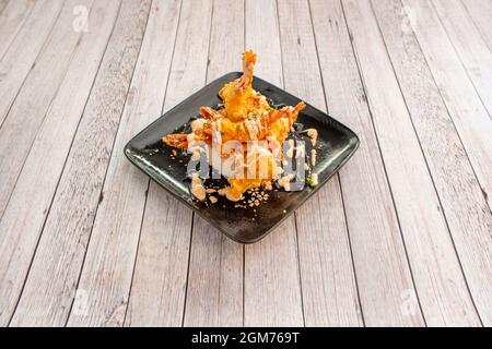 Tempura de crevettes cuisiné dans un restaurant chinois avec des assiettes noires et des tables de lumière Banque D'Images