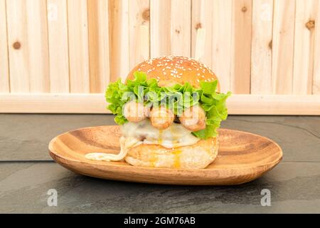 Venezuela invention de Burger avec tequeños, beaucoup de fromage et beaucoup de laitue sur ardoise noire et fond en bois Banque D'Images