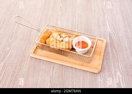 Tequeños vénézuélien farci de fromage avec sauce trempée sur un support en métal rectangulaire et une table en bambou Banque D'Images