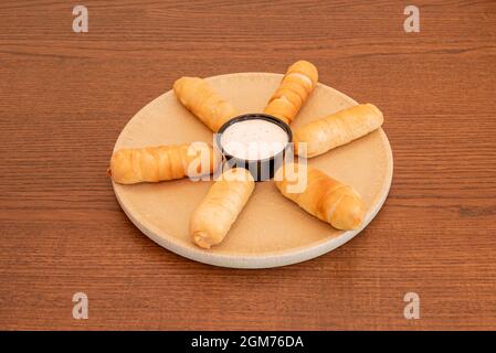 Petit-déjeuner typiquement vénézuélien avec tequeños farci de différentes saveurs sur une plaque de résine beige Banque D'Images