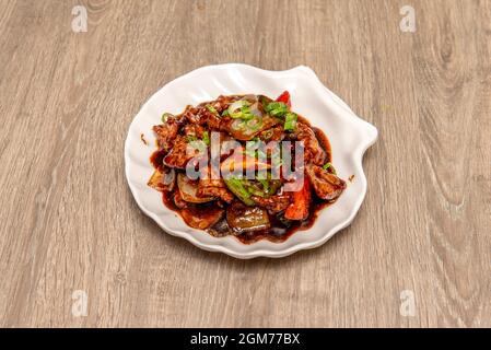 Grande recette chinoise de morceaux de bœuf, de poivrons, d'oignons et de ciboulette avec sauce à l'huître sur une assiette de noix de Saint-Jacques blanche Banque D'Images