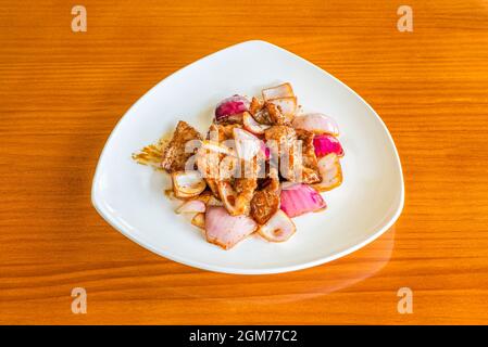 Assiette de boeuf avec oignons sautés au wok et sauce yakitori sur table de couleur cerise Banque D'Images