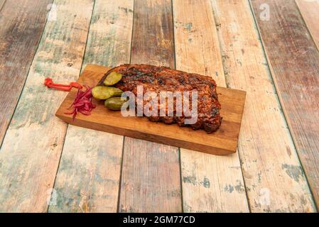 Morceau de bœuf rôti lentement avec sauce barbecue, cornichons marinés et oignon rouge Banque D'Images