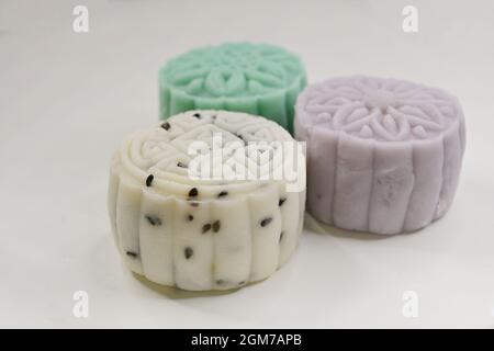 Mini-gâteaux de neige blanc, vert et violet avec garniture de sésame noir, thé vert et pâte de taro respectivement, sur fond blanc Banque D'Images