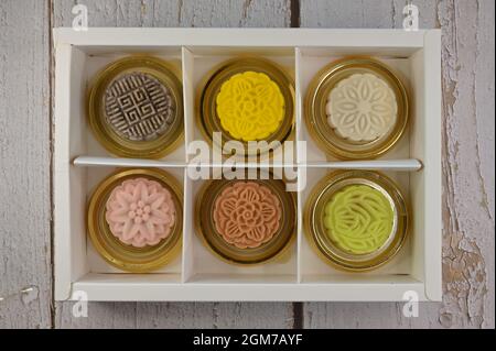 Un assortiment de mini-gâteaux de neige colorés en forme de peau de lune dans une boîte de présentation Banque D'Images