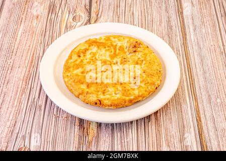 Omelette espagnole pour une personne bien cuite sur plaque blanche Banque D'Images