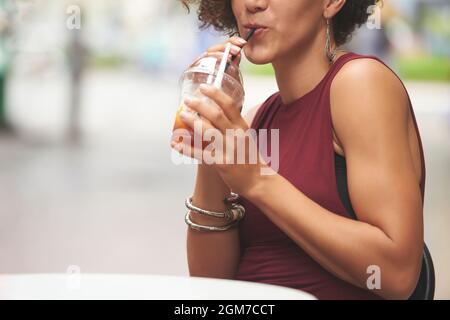 Image rognée d'une jeune femme éautiful sirotant une délicieuse boisson aux fruits lorsqu'elle est assise à une table de café à l'extérieur Banque D'Images