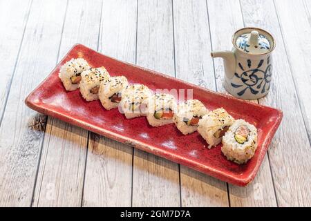 Sushis uramaki farcis à l'algue nori, au fromage, au saumon mariné, à l'avocat mûr et aux graines de sésame avec sauce soja Banque D'Images