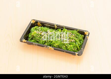 Salade populaire d'algues wakame aux graines de sésame et au pavot noir dans un récipient de livraison à domicile Banque D'Images