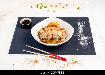 faire sauter des nouilles avec des légumes de style yakisoba, des crevettes rouges pelées, des baguettes, du sel grossier et de la sauce soja Banque D'Images