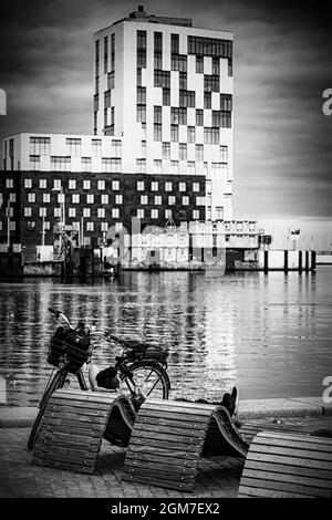 HELSINGBORG, SUÈDE - 07 SEPTEMBRE 2021 : une photographie en noir et blanc d'un homme surfant sur Internet avec le nouveau centre du commerce mondial en arrière-plan. Banque D'Images