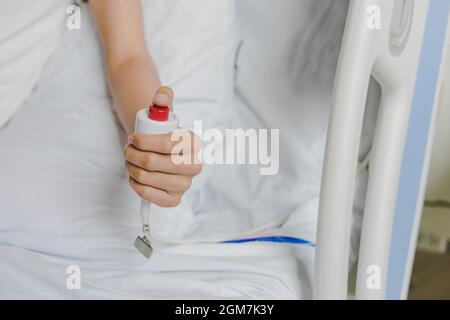 Gros plan de la main du patient appuyant sur le bouton d'urgence appelant l'infirmière en cas d'urgence à l'hôpital, les patients ont besoin d'aider à la pressine urgente et instantanée Banque D'Images