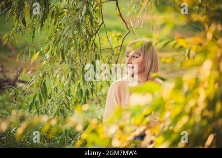 Portrait d'une femme blonde avec une courte coupe de cheveux assise sur une couverture rouge dans une clairière dans la forêt. Marche en plein air et repos dans la forêt d'automne Banque D'Images