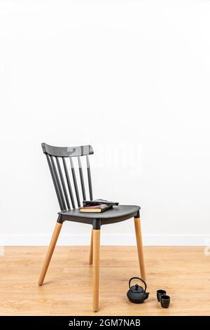 chaise noire avec bouilloire noire sur le sol et livres pour passer le temps Banque D'Images
