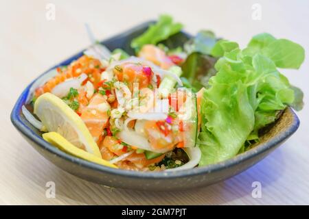 Sashimi de saumon dans une sauce chaude épicée. Dans le restaurant japonais, mélangez la cuisine japonaise et thaïlandaise entre le sashimi de saumon japonais et les herbes thaïlandaises. Banque D'Images