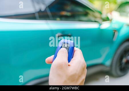 Main de l'homme en appuyant sur le bouton de la télécommande pour verrouiller ou déverrouiller la porte de la voiture dans le stationnement.mise au point douce. Banque D'Images