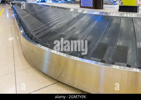 Valise sur le tapis bagages dans la zone de récupération des bagages à l'aéroport Banque D'Images