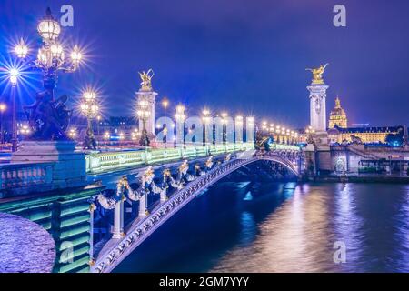 Pont Alexandre III au-dessus de la Seine et de l'Hôtel des Invalides en soirée d'été. Magnifique éclairage nocturne du pont décoré avec des ornements Banque D'Images