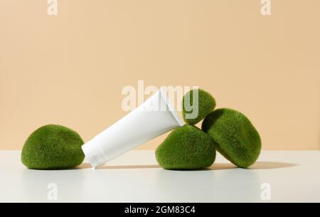 vider le tube en plastique blanc près des pierres avec de la mousse sur un fond beige. Produits cosmétiques pour le gel de marque, la crème, la lotion, le shampooing. Maquette Banque D'Images