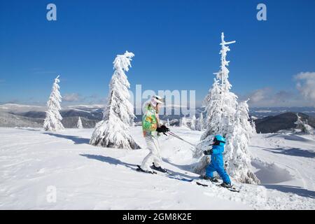 tout-petit garçon et jeune fille skier en montagne avec un casque, des lunettes, des bâtons. Course de ski pour enfants. Sports d'hiver pour la famille. Cours de ski pour enfants en alpine Banque D'Images