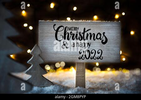 Signe avec la calligraphie anglaise Joyeux Noël et Un heureux 2022. Sapin de Noël avec lumières et neige Banque D'Images