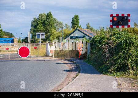 Femme cheminote barrières de passage à niveau à la traversée de grain sur l'île de grain pour permettre à un train de traverser Banque D'Images