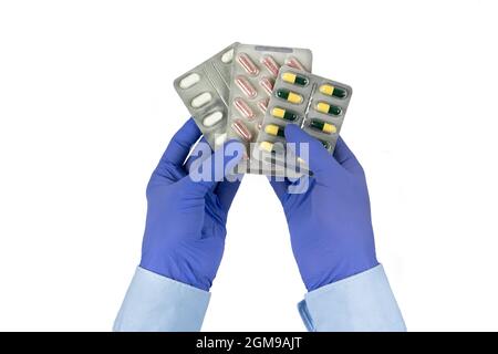 Boîtes de pilules dans les mains de médecins isolées sur fond blanc mains de mâles dans des gants en latex bleu. Banque D'Images